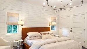 Une chambre à coucher avec un grand lit, deux tables de chevet, une chaise, un lustre et une armoire.
