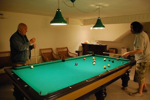 A pool table in a room with chairs and a cabinet. - Icirliev Alacati (Çeşme)