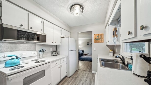 A modern kitchen with white cabinets, a stainless steel stove, and a blue kettle. - Quaint Stillwater Retreat Minutes from Historic Downtown - Lilac Apartment (Stillwater)