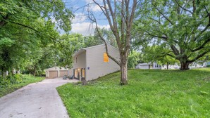 A single-story house with a garage, surrounded by trees and a grassy area. - Accessible 3-Bedroom Retreat Near Historic Downtown Stillwater - Morning Glory (Stillwater)