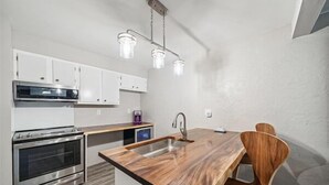 A modern kitchen with stainless steel appliances, a wooden island with a sink, and pendant lighting. - Accessible 3-Bedroom Retreat Near Historic Downtown Stillwater - Morning Glory (Stillwater)