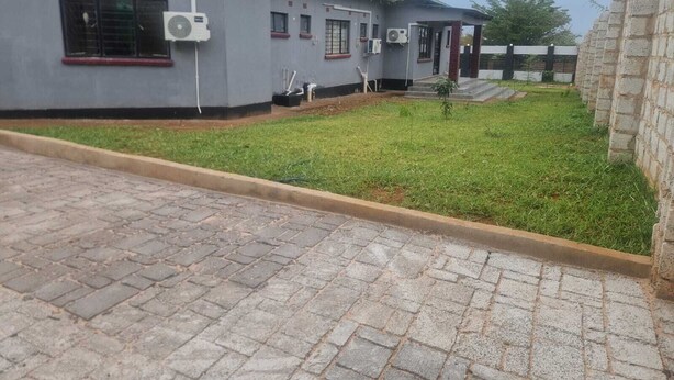 Un edificio con techo verde, unidades de aire acondicionado y entrada pavimentada.