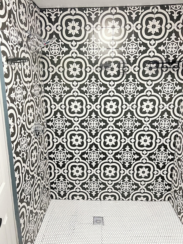 A bathroom with black and white patterned tiles, a shower area, and a visible drain.