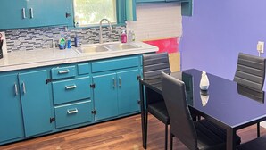 A kitchen with teal cabinets, a sink, and a dining area with a black table and chairs. - Pet friendly Brand new home in Central Oklahoma City (Oklahoma City)