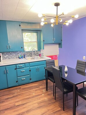 A kitchen with teal cabinets, a sink, and a dining area with a table and chairs.