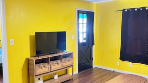 A room with yellow walls, a wooden entertainment center, a ceiling fan, and a door with a window. - Pet friendly Brand new home in Central Oklahoma City (Oklahoma City)