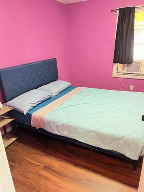 A room with a bed, a window with a black curtain, and a wall heater.