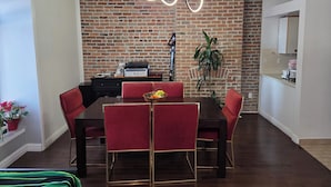 Un espace repas avec un mur en briques, un luminaire moderne et des chaises rouges.