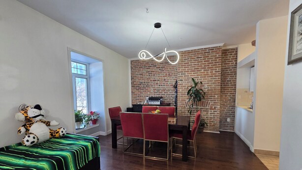 Un salon moderne avec un coin repas, un mur en briques et une grande fenêtre.
