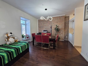 A modern living room with a dining area, a brick wall, and a large window.