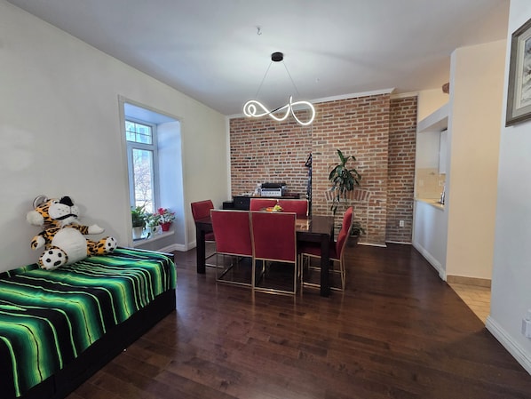Un salon moderne avec un coin repas, un mur en briques et une grande fenêtre.