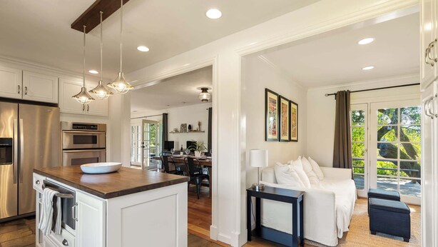 A modern kitchen with a central island, a dining area with a table and chairs, a living room with a sofa and a coffee table, and a view of the outdoors through a glass door. - Oak and Stone | Pool + Glen Ellen Wine Country (Glen Ellen)
