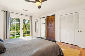 A bedroom with a bed, a ceiling fan, a sliding door, and a view of greenery outside. - Oak and Stone | Pool + Glen Ellen Wine Country (Glen Ellen)