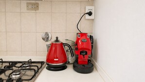 Ett kök med en gasspis, en röd vattenkokare och en röd elektrisk vattenkokare som är ansluten till ett vägguttag.