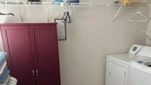Una sala de bugaderia amb un armari vermell, una rentadora i un escorredor.
