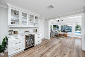 Eine moderne Küche mit weißen Schränken, einem eingebauten Kühlschrank und Blick auf einen Pool durch große Fenster.