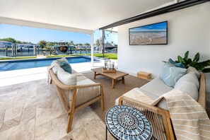 Ein moderner Außenbereich mit Pool, Korbmöbeln und Blick auf den Strand.