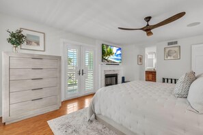 A bedroom with a bed, a ceiling fan, a television, a fireplace, and a wardrobe. - Casa Solmar (Treasure Island)