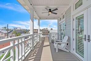 A covered deck with a ceiling fan, a grill, and white Adirondack chairs. - Casa Solmar (Treasure Island)