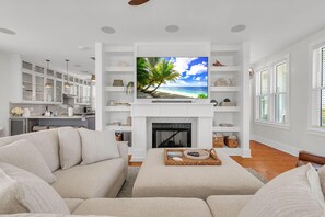 A living room with a TV, white furniture, and a fireplace. - Casa Solmar (Treasure Island)