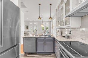 A modern kitchen with a central island, stainless steel appliances, and pendant lighting. - Casa Solmar (Treasure Island)