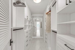 A narrow hallway with white storage units, a hanging shoe rack, and a view into a room with a door. - Casa Solmar (Treasure Island)
