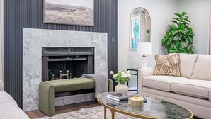 A living room with a fireplace, a sofa, a coffee table, and a large plant.