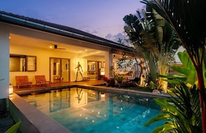 A modern house with a swimming pool, glass doors, and a well-lit interior. - Almara Boutique Villa - Private Spa Bang tao Beach (Choeng Thale)