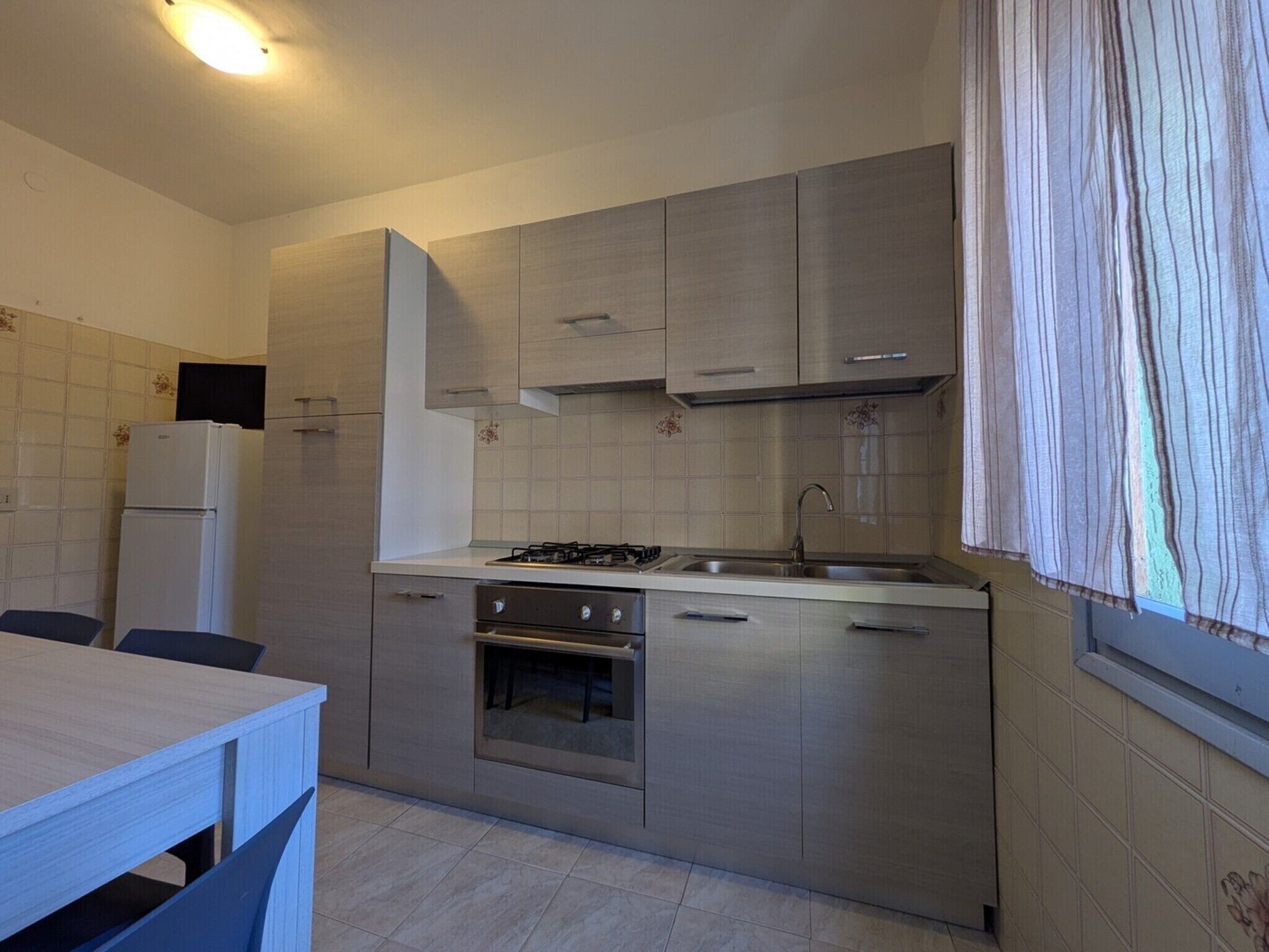 A compact kitchen with a gas stove, oven, sink, and a refrigerator.
