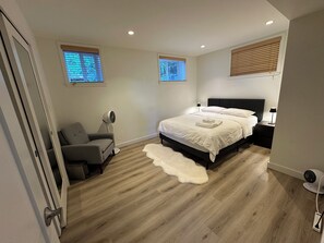 Une chambre à coucher avec un lit, des tables de chevet, une chaise, un ventilateur et une fenêtre.