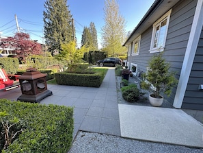 Une allée menant à une maison, bordée de différentes plantes et d’un lampadaire.