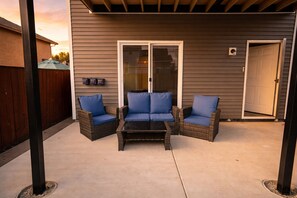 Un patio al aire libre con mobiliario de mimbre y un ventanal de vidrio.
