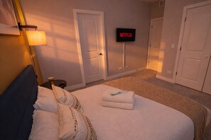 Une chambre dâhĂŽtel avec un lit, un tĂ©lĂ©viseur fixĂ© au mur et une porte.