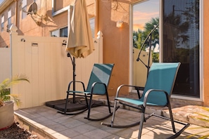 A patio with two rocking chairs, a potted plant, and a white fence. - Enchanting Townhome, minutes to Disney World, Universal Studios. Pool, Gated (Kissimmee)