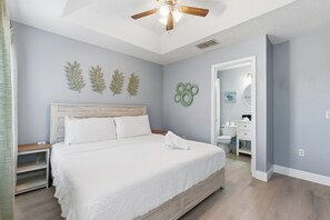 A bedroom with a bed, a ceiling fan, a nightstand, a dresser, and a bathroom visible through an open door. - Enchanting Townhome, minutes to Disney World, Universal Studios. Pool, Gated (Kissimmee)
