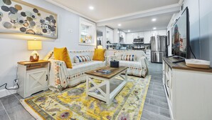 Een moderne woonkamer met een zithoek, salontafel en een keuken op de achtergrond.