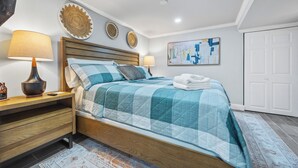 Een slaapkamer met een houten bed, twee nachtkastjes, een wandlamp, decoratieve borden en een schilderij.