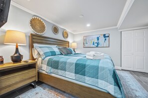 A bedroom with a wooden bed, two bedside tables, a wall-mounted lamp, decorative plates, and a painting. - Beautiful Buckhead Unit + Direct MARTA to World Cup Stadium + King Bed (Atlanta)