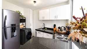 Eine moderne Küche mit Kühlschrank aus Edelstahl, Waschmaschine, Spüle und Herd.
