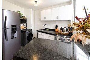 A modern kitchen with a stainless steel refrigerator, a washing machine, a sink, and a stove. - It's Always Sunny in this Roma Norte Apartment (Mexico City)