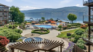 A resort with multiple swimming pools, a sun deck, and a view of a lake and mountains.