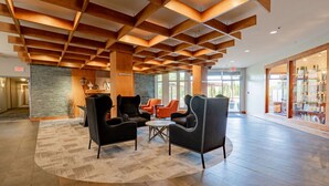A lobby with a wooden ceiling, a stone wall, and a seating area with chairs and a table.