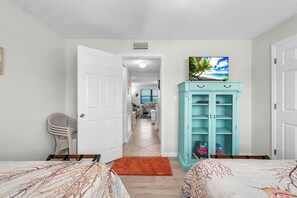 Un dormitorio con dos camas, un armario color turquesa y un pasillo que conduce a una sala de estar.
