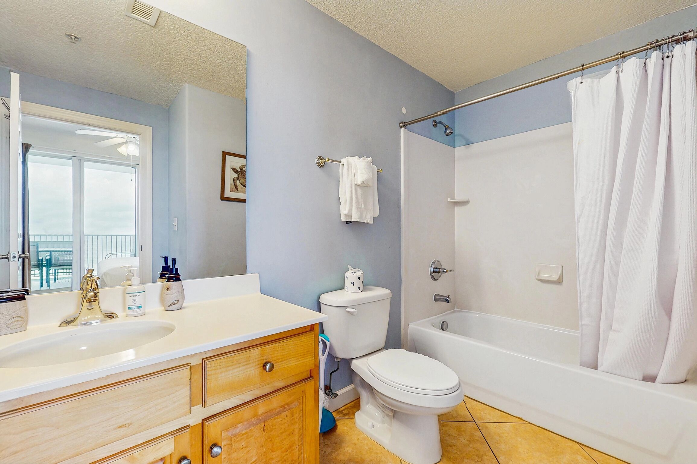 A bathroom with a sink, toilet, bathtub, and shower curtain.