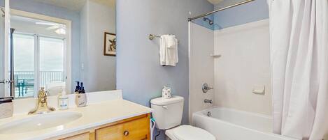 A bathroom with a sink, toilet, bathtub, and shower curtain.