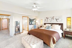 A bedroom with a large bed, a ceiling fan, a nightstand, and a wall-mounted lamp. - Oceanfront | Game Room | Clamming | Deck (Ocean Shores)