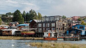 Una propiedad frente al agua con un edificio moderno, barcos y cisnes.