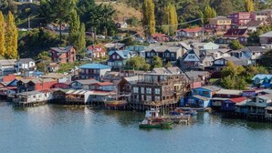 Una comunidad frente al agua con casas sobre pilotes, barcos y una vista despejada del agua.