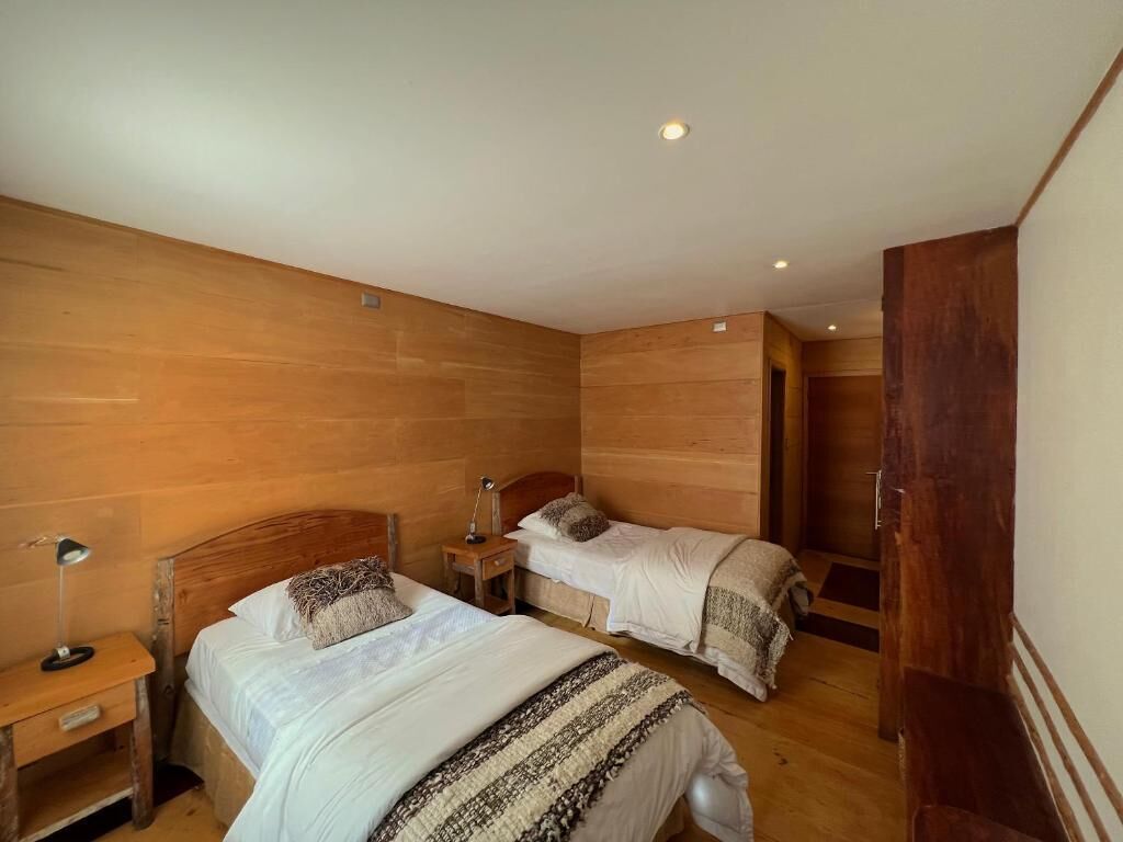 A room with two beds, wooden walls, and a door.