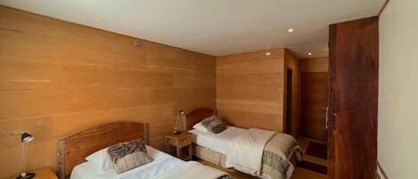A room with two beds, wooden walls, and a door.